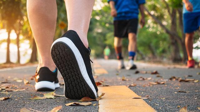 The sole of a sneaker walking on a pathway.