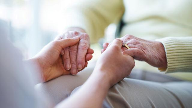 close up of caregiver holding a senior woman's hands