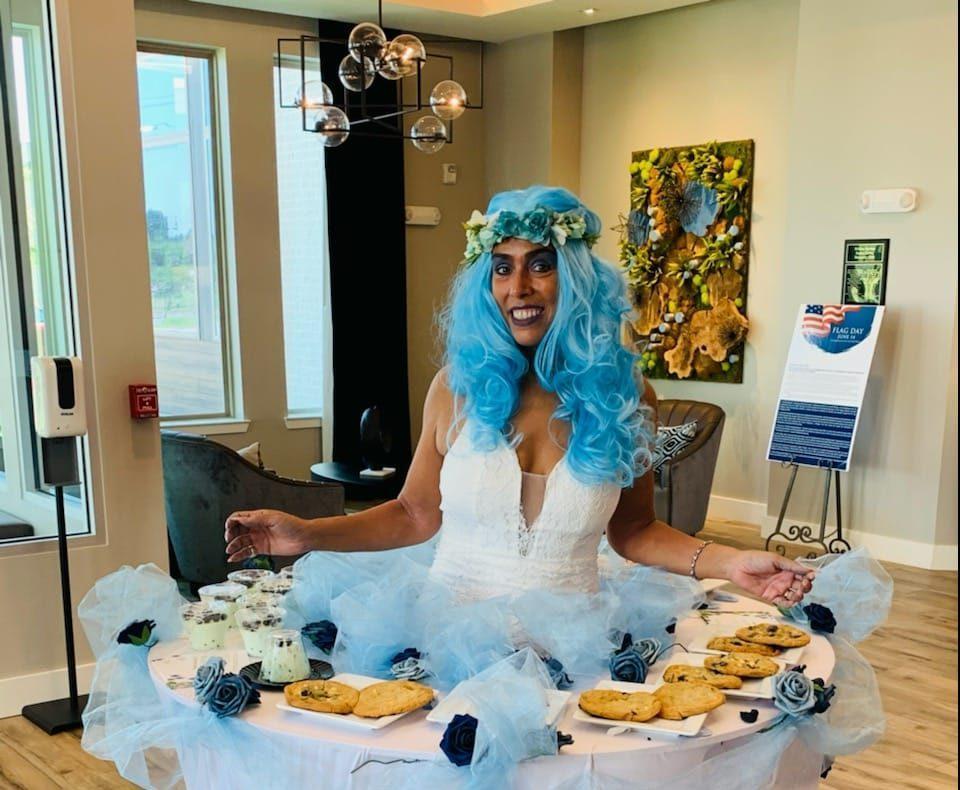 Employee wearing a blue fairy outfit with multiple baked goods