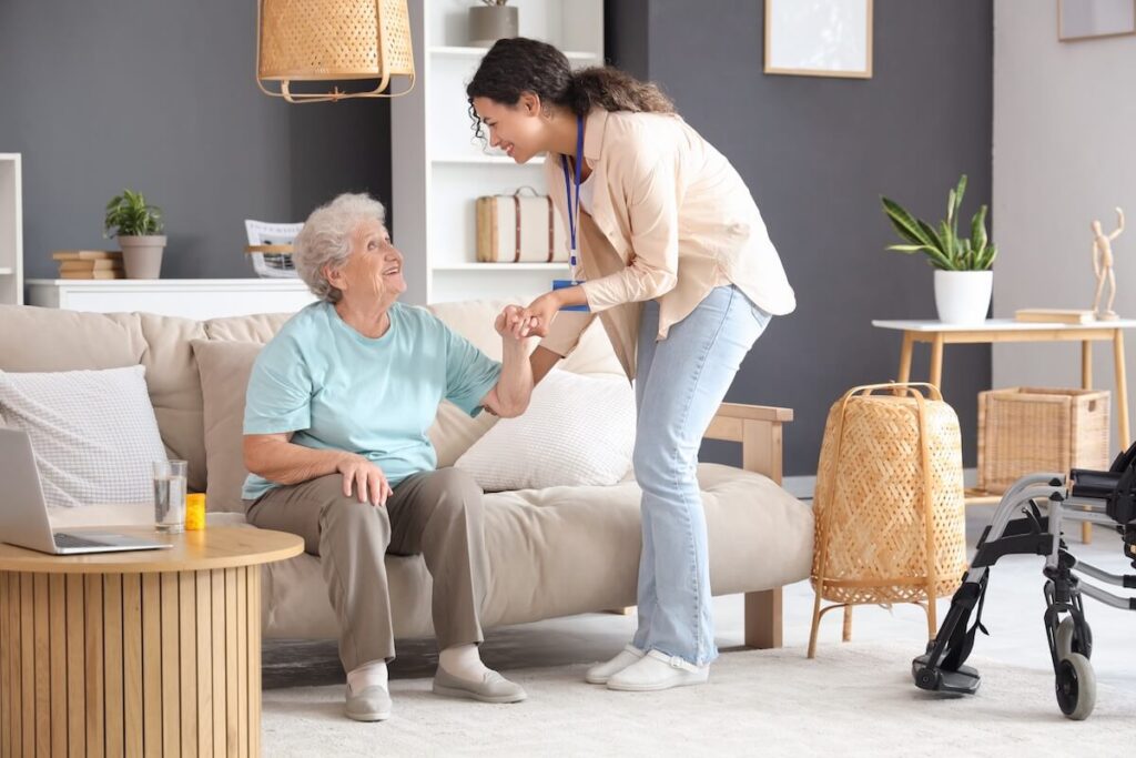 Young African-American female medical worker helping elderly woman in nursing home